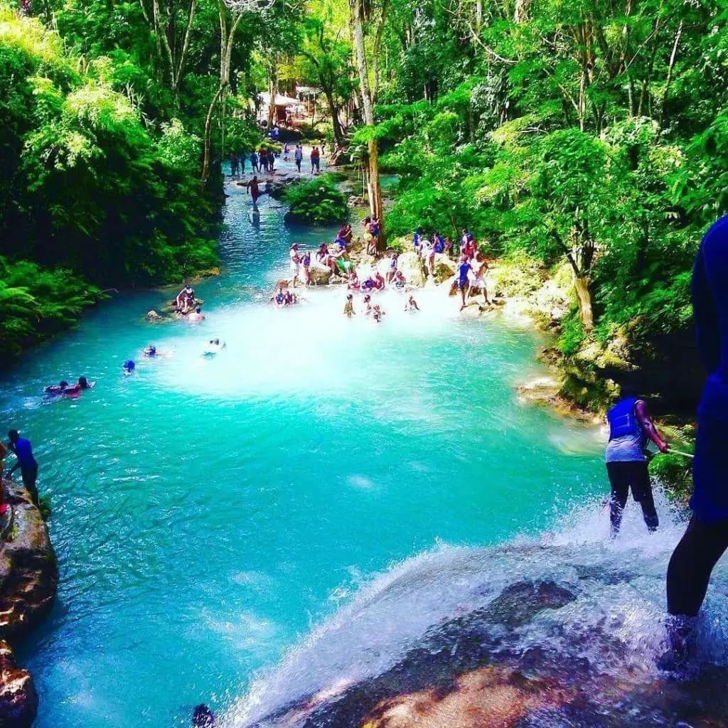 Guests swimming in a turquoise blue lagoon surrounded by Jamaican rainforest